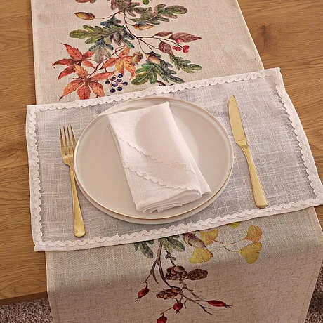 Een tafelloper bedrukt met vrolijke bladeren in herfstkleuren siert de gedekte tafel en zorgt zo voor een gezellige maaltijd.