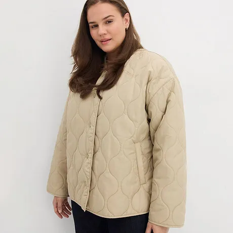 Beige gewatteerde jas met knopen, gecombineerd met een donkere broek.