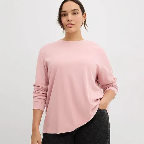 De zachtroze longsleeve met ronde hals past perfect bij de donkere broek.