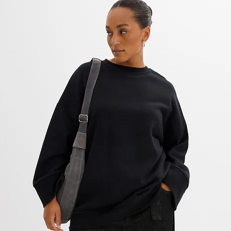 Zwarte sweater met een ronde hals en een grijze schoudertas.