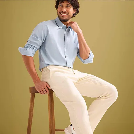 Lichtblauw overhemd met hoog opgerolde mouwen en een beige pantalon.