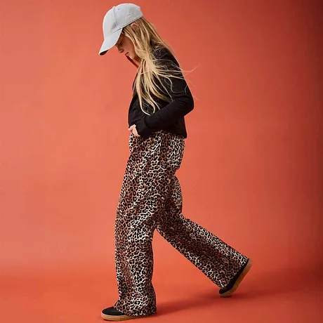 Zwarte trui gedragen op een broek met luipaardprint. De witte pet maakt de look helemaal compleet.