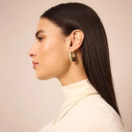 Elegante crèmekleurige coltrui, minimalistisch en stijlvol. Gouden oorringen als enige sieraden.