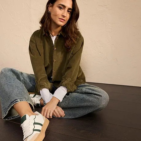 Olijfgroene blouse met jeans en witte sneakers met groene strepen