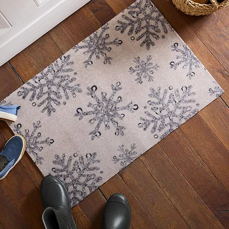 Winterse deurmat met sneeuwvlokmotief op houten vloer.