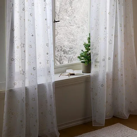 Gordijnen omlijsten het raam met zicht op een winters landschap.