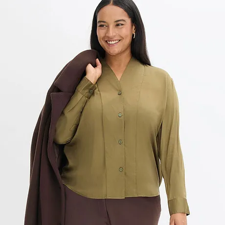 Elegante combinatie van olijfgroene blouse en bruine jas.