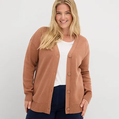 Roestkleurig vest over witte top, gecombineerd met donkere jeans.