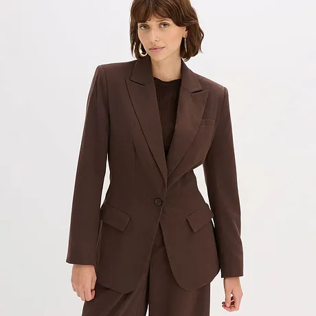 Bruine blazer en bruine broek gecombineerd met zwarte top.
