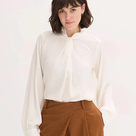 Witte blouse met strikkraag, gecombineerd met bruine broek.