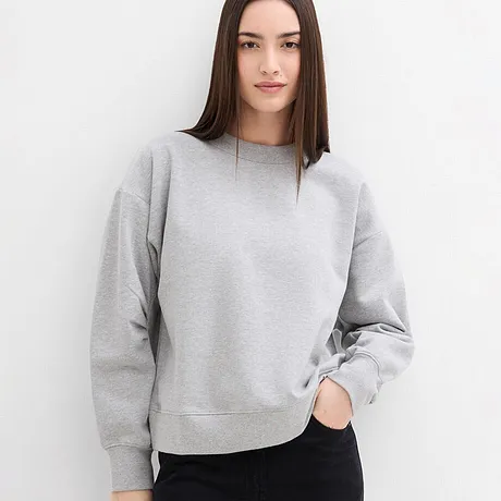 Minimalistische grijze sweater met ronde hals, gecombineerd met donkere broek.