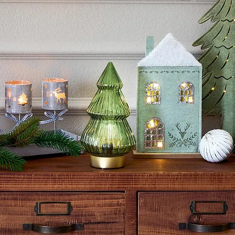 Feestelijke kerstverlichting met huisje, kaarsen en groene dennenboom.