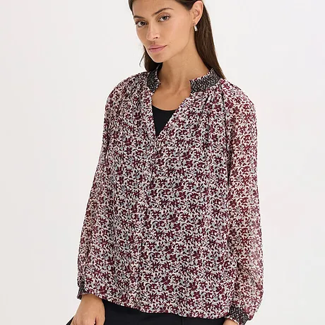 Blouse met floraal patroon in zwart, rood en wit.