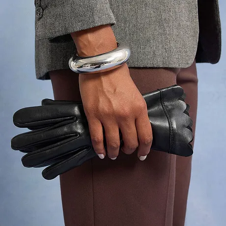 Zilveren armband en zwarte imitatieleren handschoenen.