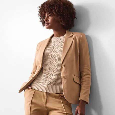 Beige blazer gecombineerd met crèmekleurige gebreide trui.