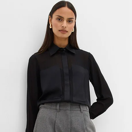 Zwarte blouse gecombineerd met grijze broek.