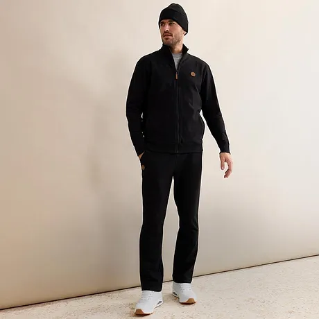 Zwart joggingpak met muts en witte sneakers.