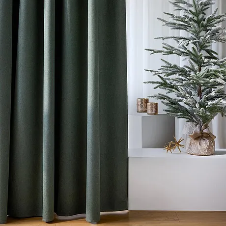 Donkere gordijnen omlijsten de feestelijke kerstboom.