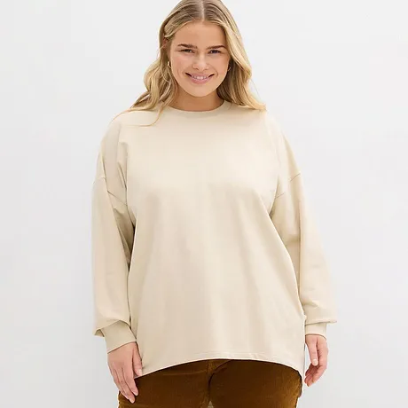 Crèmekleurige sweater met ronde hals gecombineerd met bruine broek.