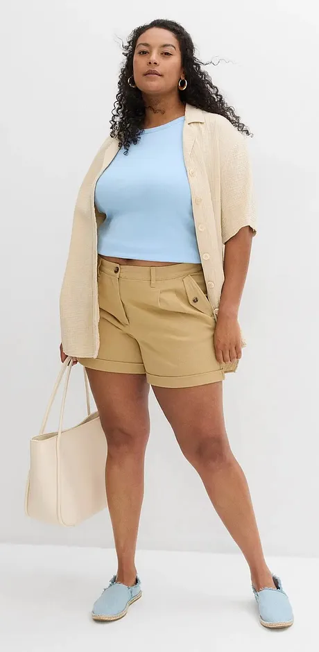 Zomerse outfit met een lichtblauw topje, beige cardigan, khaki shorts en bijpassende schoenen.