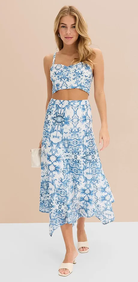 Zomerse tweedelige outfit met een blauw-wit bloemenpatroon: crop top en een lange rok met een asymmetrische zoom.