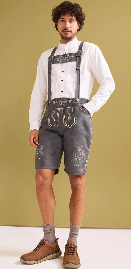 Wit overhemd, grijze lederhosen met bretels, korte sokken en bruine schoenen.