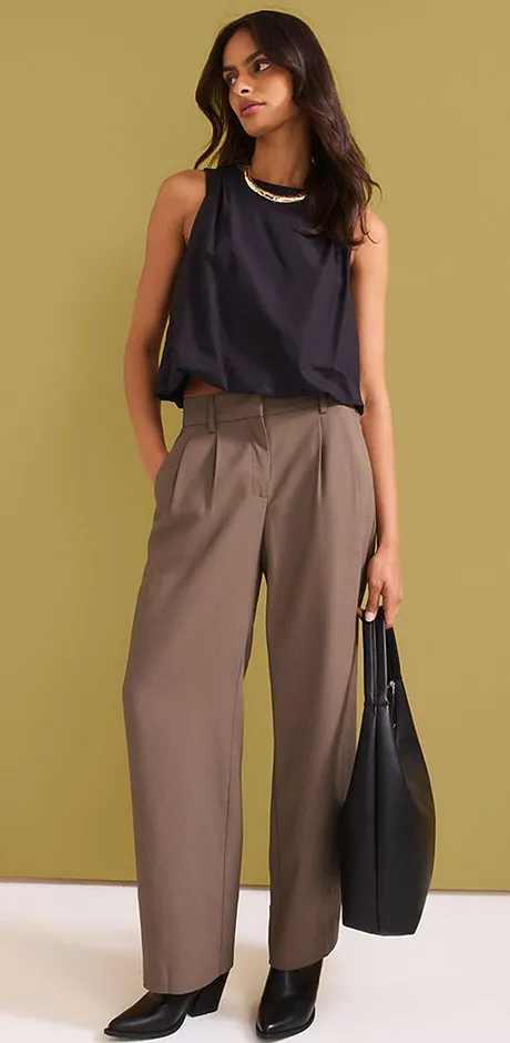 Outfit met een donker haltertop, wijde beige broeken en een zwarte handtas.