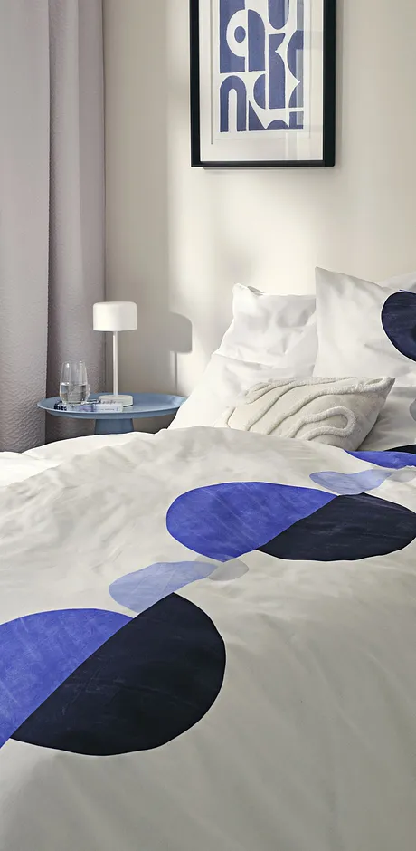 Modern bedlinnen met een geometrisch patroon in blauw en zwart op een witte achtergrond.
