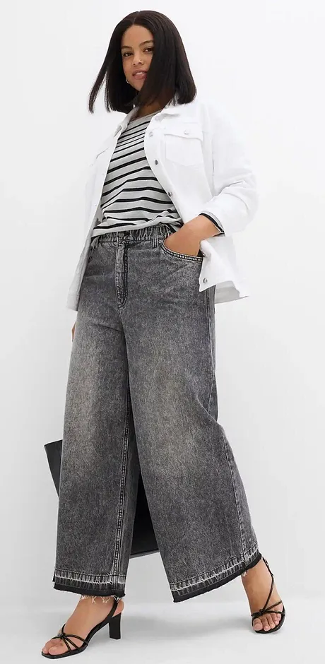 Wijde spijkerbroek, gestreept topje en witte jas vormen een casual, moderne look.