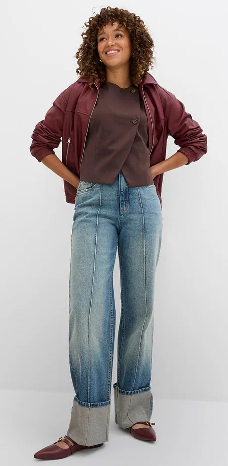 Casual herfstlook met een wijnrode jas, grijs T-shirt en wijde jeans met omslag.