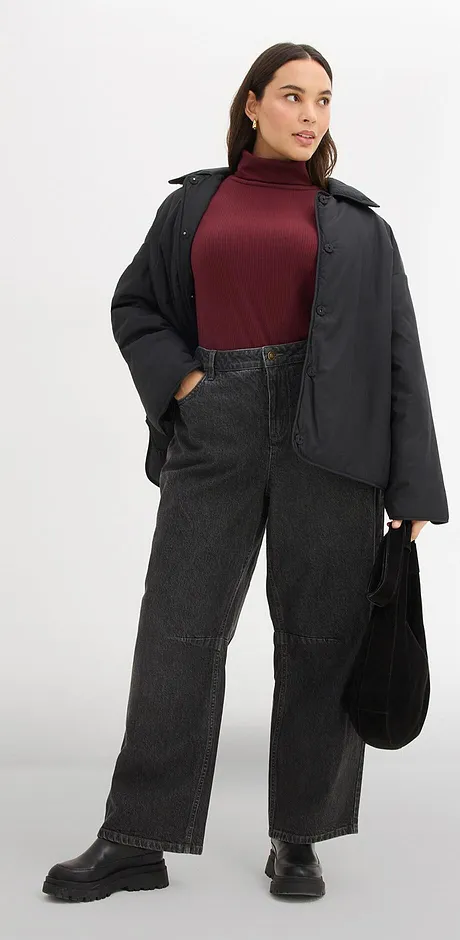 Combinatie van een donkerrode coltrui met een zwarte jas en zwarte jeans.