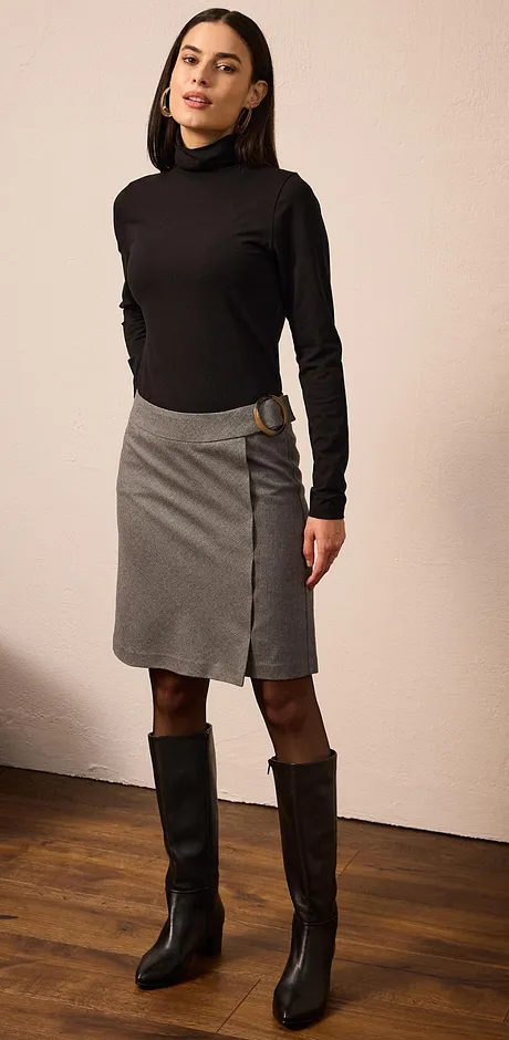 Elegante look met een zwarte coltrui, grijze rok en hoge zwarte laarzen.