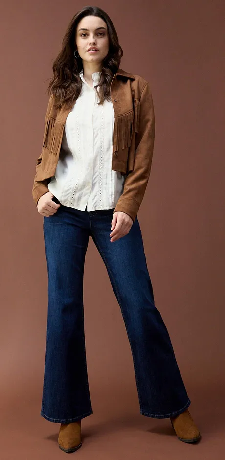 Jack in wildleder look over witte blouse, gecombineerd met uitlopende jeans.