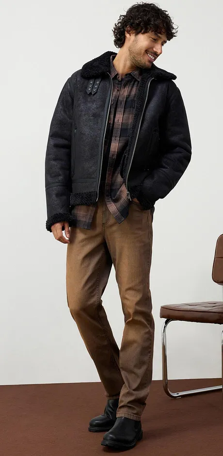 Casual bruine jeans, geruit overhemd en zwarte imitatieleren boots.