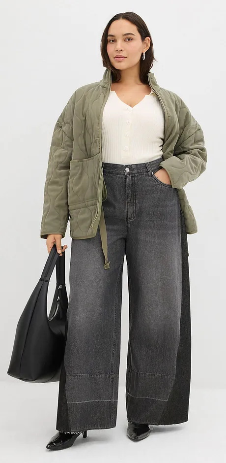 Olijfgroene gewatteerde jas, witte top en wijde grijze jeans.