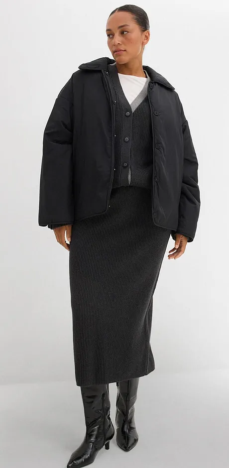 Gewatteerde jas, lange rok en imitatieleren laarzen. Minimalistisch wit shirt eronder.