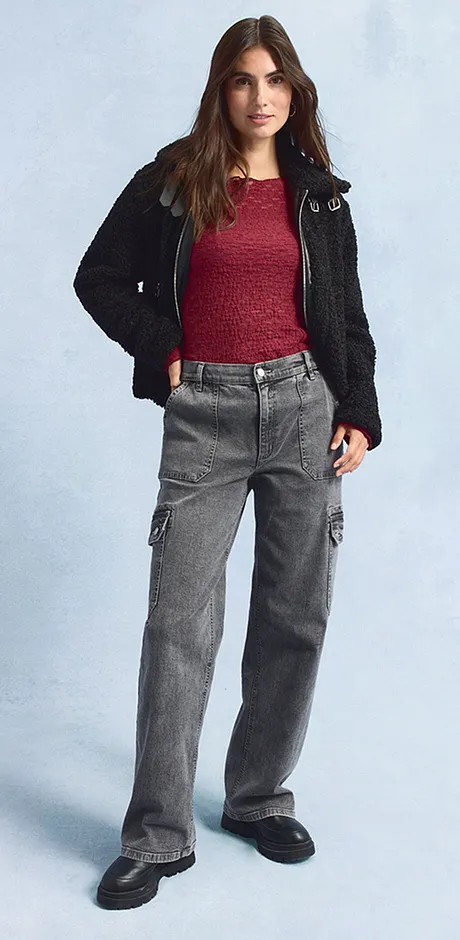 Zwarte jas, rood shirt, wijde grijze jeans en donkere schoenen.