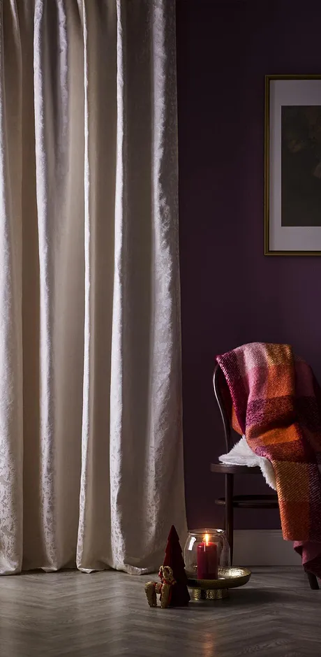 Licht gordijn omlijst het raam mooi. Stoel met warme deken eroverheen.