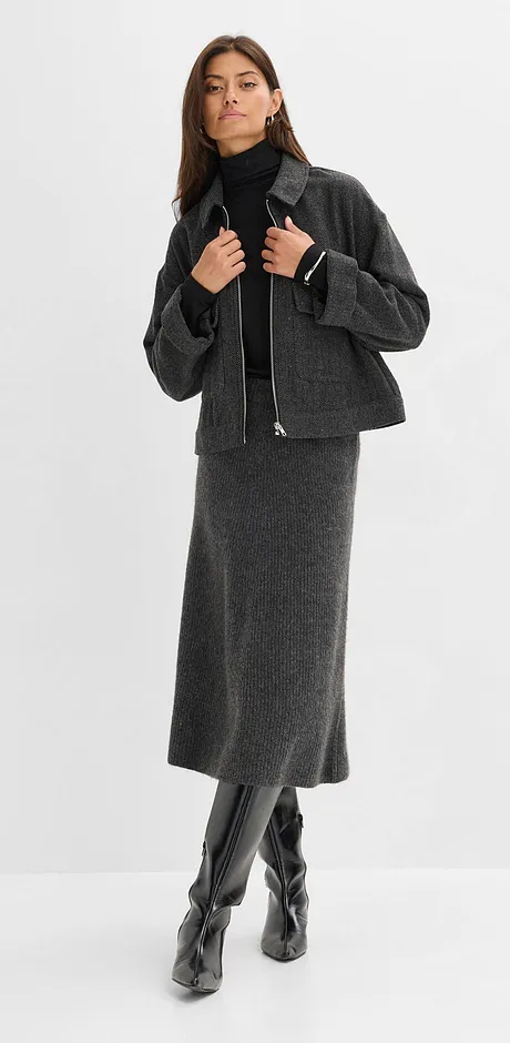 Grijze wollen rok, zwarte coltrui, korte jas en kniehoge imitatieleren laarzen.