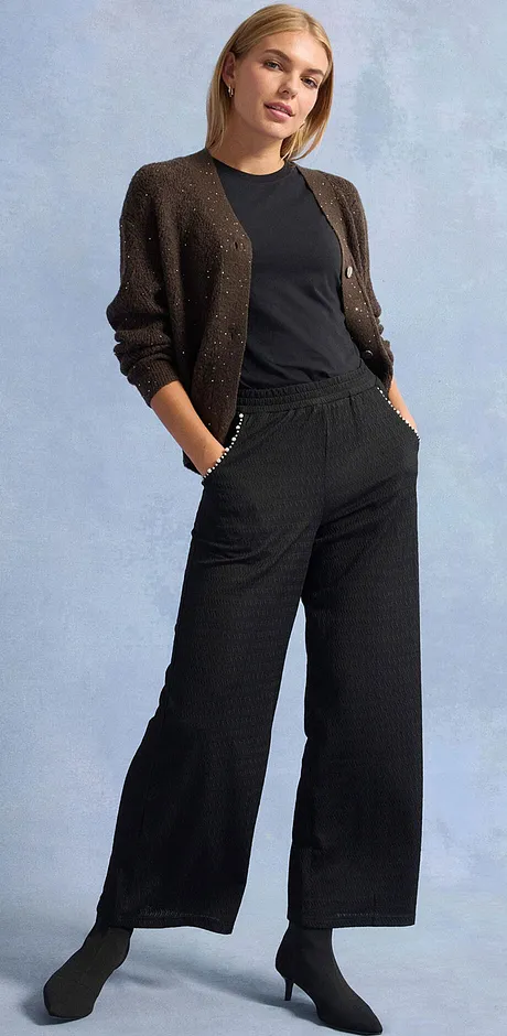 Zwarte broek, T-shirt en glinsterend gebreid vest.