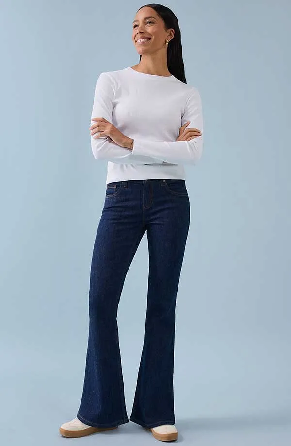 Wit shirt met lange mouwen gecombineerd met donkerblauwe wijde jeans voor een tijdloze, elegante uitstraling.