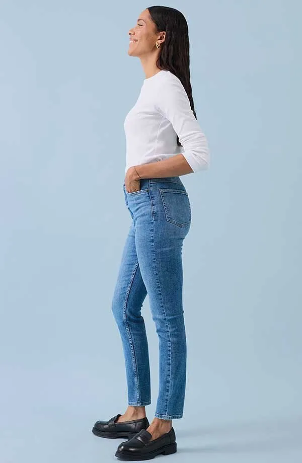 Casual look met wit shirt met lange mouwen, nauwsluitende blauwe jeans en zwarte leren schoenen.