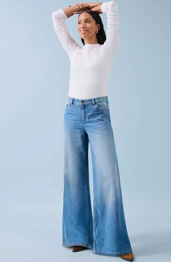 Wit shirt met lange mouwen en wijde jeans: een combinatie van comfort en casual stijl.