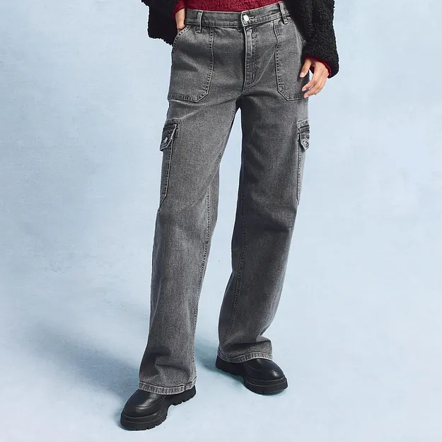 Grijze cargo jeans met ruime zijzakken, gecombineerd met zwarte schoenen.