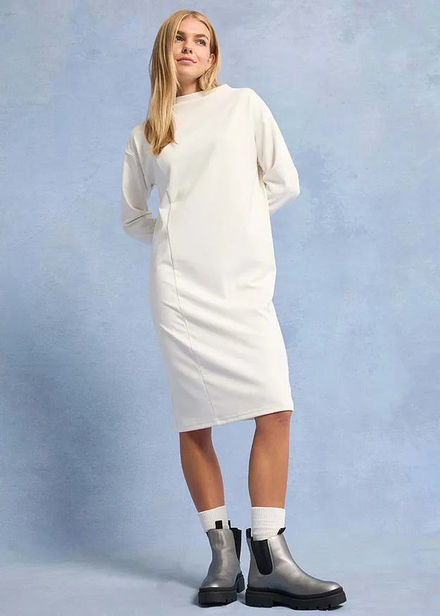 Minimalistische witte jurk met lange mouwen, gecombineerd met grijze Chelsea boots en witte sokken.