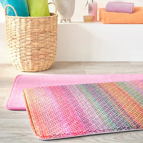 Vrolijk gekleurde handdoeken met een bijpassende badmat zorgen voor een frisse badkamer.