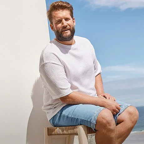 Casual zomerlook: wit T-shirt en een lichtblauwe jeans short voor een relaxte dag aan het strand.