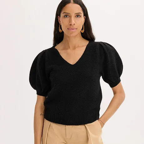 Zwarte trui met pofmouwen en V-hals, gecombineerd met een beige broek.