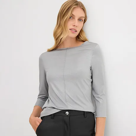 Eenvoudig grijs shirt met driekwartmouwen, tijdloos elegant gecombineerd met een donkere broek.