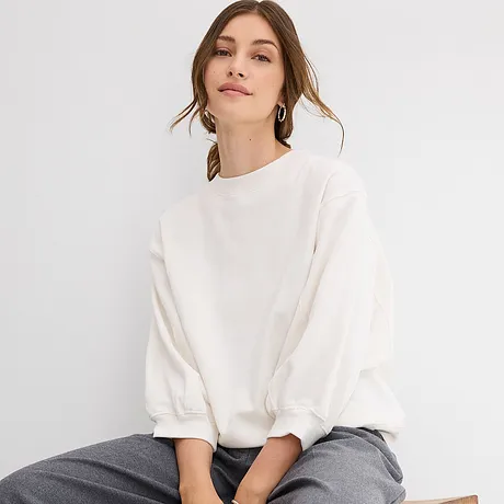 Wit oversized sweatshirt met wijde mouwen, gecombineerd met een grijze broek.